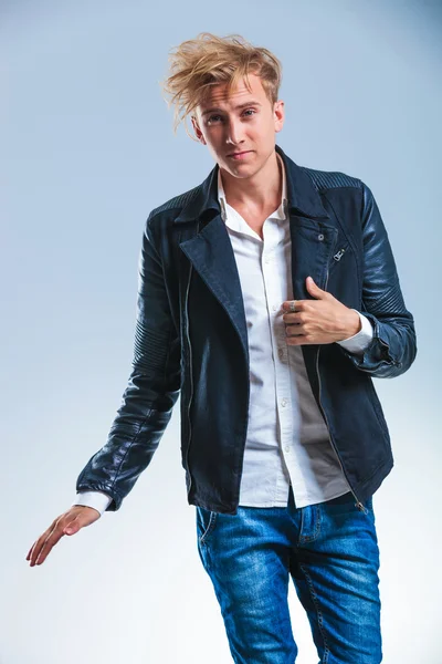 Young man holding his leather jacket while smiling at the camera — Stock Photo, Image