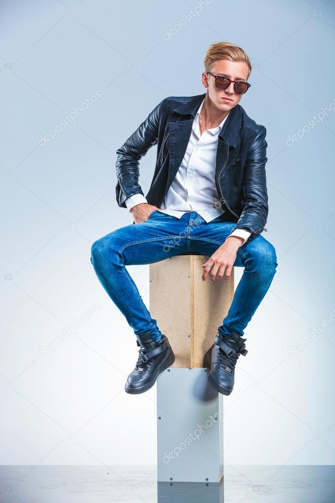 boy holding his hand in pocket is posing while sitting on boxes