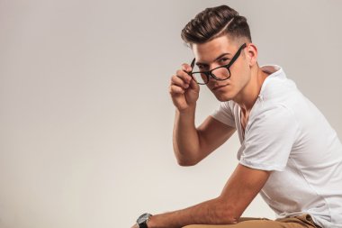 portrait of stylish young man taking off glasses