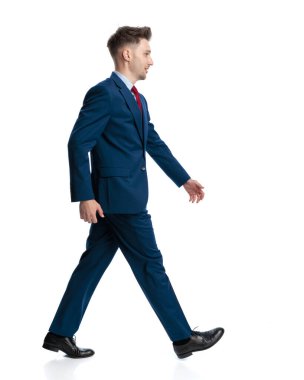 Mavili lacivert takım elbiseli, beyaz arka planda yürüyen seksi bir genç görüyorum.