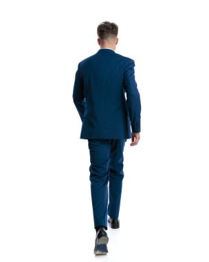 Lacivert takımlı şık moda adamının beyaz arka planda ilerleyişinin arkasında.