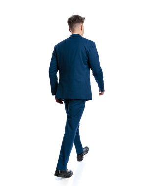 Beyaz arka planda yürüyen lacivert takım elbiseli zarif genç işadamının arka planı.