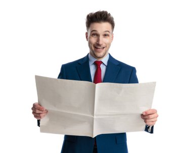 Lacivert takımlı mutlu, zarif adam beyaz arka planda gülümseyip gazete okuyor.