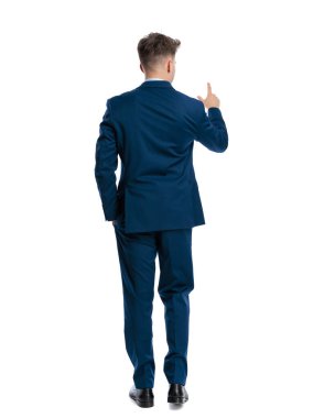 Lacivert takım elbiseli zarif bir işadamının arka planda el ele yürüdüğünü ve beyaz arka planda parmak gösterdiğini gördüm.