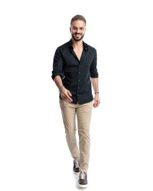 Gözlüklü mutlu bir adam, beyaz arka planda yürüyor ve gülümsüyor.