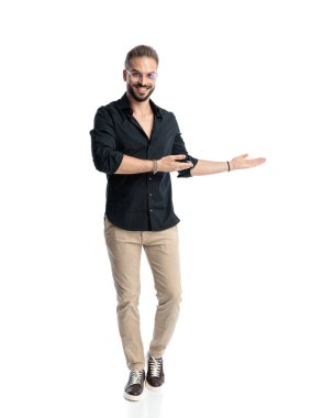 Beyaz arka planda yürürken gülümseyen ve yüzünü gösteren gözlüklü çekici genç bir adam.