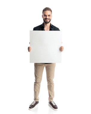 Gözlüklü, gülümseyen ve beyaz arka planda boş tahtayı tutan gururlu sıradan bir adam.