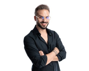 Gözlüklü, kolları çapraz seksi bir adam. Önüne bakıyor ve beyaz arka planda gülümsüyor.