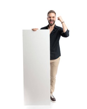 heyecanlı sıradan bir adam yumruklarını kaldırıp zaferi kutlarken tahtayı tutuyor ve beyaz arka planda gülümsüyor.