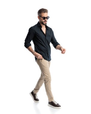 Güneş gözlüklü sıradan bir genç, beyaz arka planda el ele yürüyor.