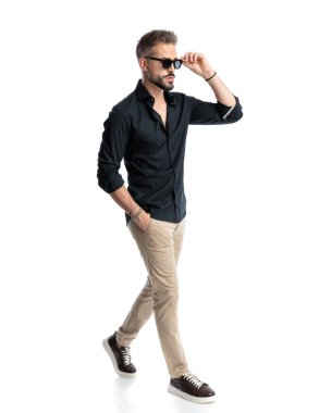 Güneş gözlüğü takan ve arka planda el ele tutuşan kendine güvenen genç adamın yan görünüşü