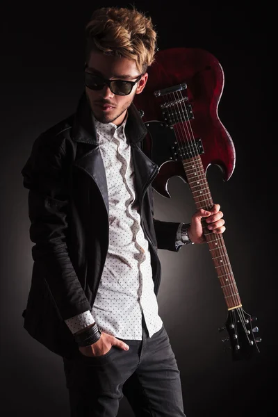 Rocker holding his guitar on shoulder and looking back — Stock Photo, Image