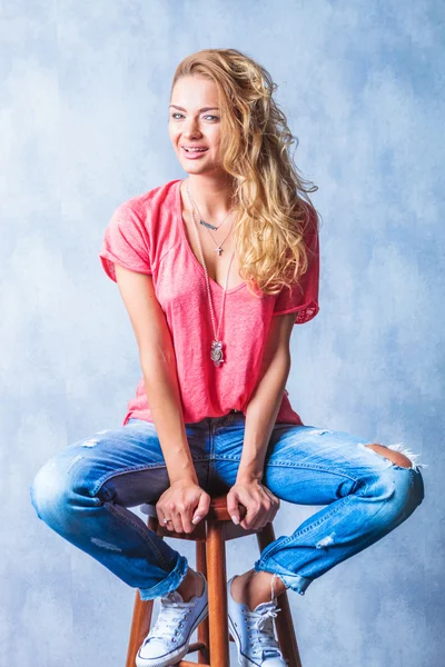 Schöne Frau lächelt in die Kamera, während sie auf einem Stuhl sitzt — Stockfoto