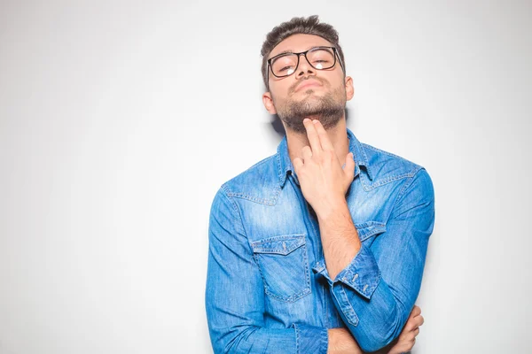 Young man looking down at the camera while pointing to his chin — Stock Photo, Image
