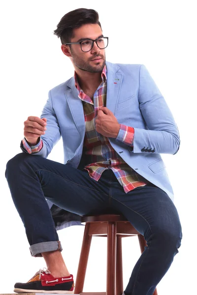 Fashion man sitting while fixing his jacket — Stock Photo, Image