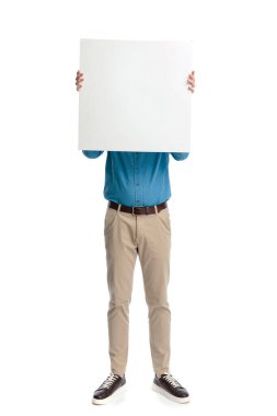 Mavi gömlekli genç adam beyaz arka planda izole edilmiş beyaz bir tahtanın arkasında dikiliyor ve yüzünü gizliyor..
