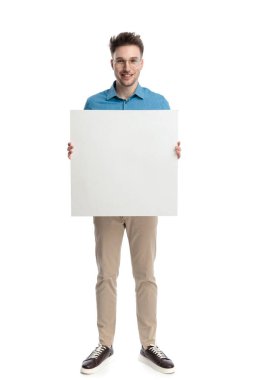 Gözlüklü mutlu genç adam elinde beyaz bir tahtayla dikiliyor, beyaz arka planda izole bir şekilde gülümsüyor..