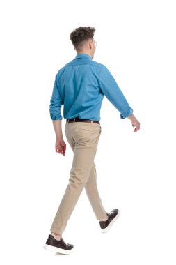 Gözlüklü, yürüyen ve yana bakan, beyaz arka planda izole genç bir adamın arka planı..