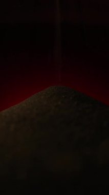 Ilık kırmızı ışık altında yavaşça dönen koyu kumlar, süreklilik, sabır ve ahengi temsil eder.