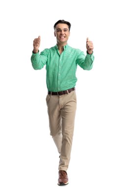Mutlu, genç, sıradan bir adam, beyaz arka planda izole edilmiş baş parmak hareketi yapıyor.