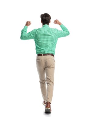 Muzaffer bir adamın yürüyüp başarısını kutlarken beyaz arka planda yumruklarını havaya kaldırması.