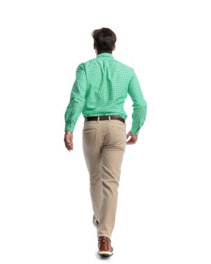 Beyaz arka planda yürüyüp giden sıradan bir genç adam.