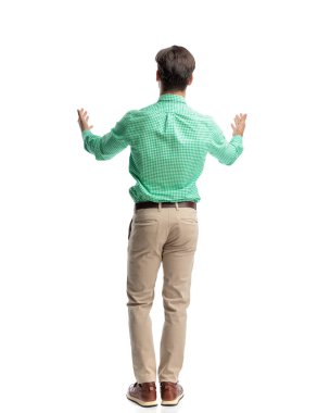 Yeşil kareli gömlek ve bej pantolon giyen, beyaz arka planda kolları açık bir şekilde el kol hareketi yapan sıradan bir adamı selamlıyoruz.