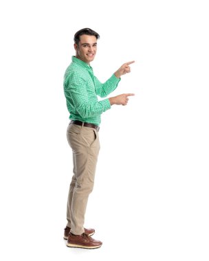Neşeli, sıradan bir adam, iki eli de yeşil kareli gömlek ve bej pantolon giymiş, beyaz arka planda izole bir şekilde ileriye bakıyor.