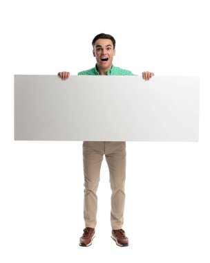 Heyecanlı sıradan bir adam iki eliyle büyük boş bir pankart tutuyor ve beyaz arka planda ileriye bakarken bağırıyor.