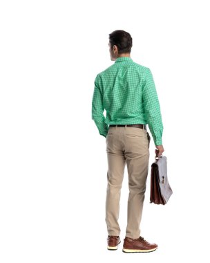 Yeşil kareli gömlek ve bej pantolon giyen, deri evrak çantası tutan, el ele tutuşan, beyaz arka planda beklemekte olan akıllı bir adamın arka görüntüsü.