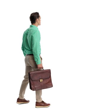 Kareli gömlekli, deri çantalı ve beyaz arka plana bakarken yürüyüp giden sıradan bir genç.