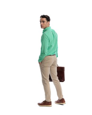 Ciddi bir adam el ele tutuşup çantasını tutuyor ve beyaz arka plana bakıyor.