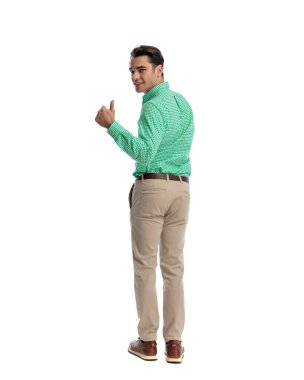 Pozitif, arkası dönük bir adam arkasını döndü, omuz üzerinden bakıyor ve beyaz arka planda izole bir baş parmak işareti gösteriyor