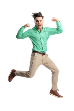 Enerjik genç adam beyaz arka planda ileriye bakarken havaya atlıyor ve kaslarını kasıyor.