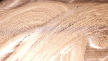 Dinamik yakın plan fırça, kıvrımlı, katmanlı darbeler parlak altın boya boyunca, fiziksel araç hareketi vurguluyor.