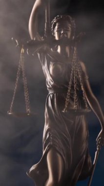 Gözleri bağlı bir kadının bronz heykeli etrafında yoğun bir sis süzülüyor. Elinde denge ve kılıç var..