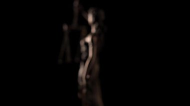 Adalet Anıtı 'nın bronz heykeli, siyah arka planda pullar ve kılıç tutarken çekilmiş..