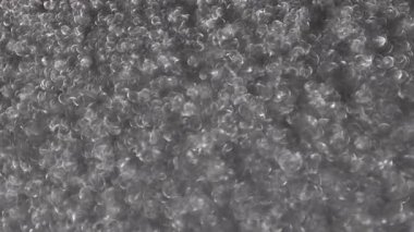 Işıldayan platin bir yüzeyin yoğun gümüş bokeh çemberleriyle parıldayan, odaktan uzak, soyut bir görüntüsü.