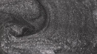 Kum dokusu ve yüzeyinde ışıl ışıl parlayan parçacıklar olan girdap şeklinde dönen koyu gümüş rengin ayrıntılı görüntüsü.