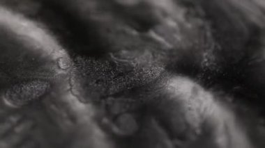 Koyu titanyum boya, kumlu bir dokuya sahip ağır bir şekilde akıyor. Derin dalgalanan çıkıntılar oluşturuyor ve yüzeyde parlak metalik parçacıklar sergiliyor.