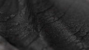 Koyu titanyum boya, özel kumlu bir yapıyla yavaşça akıyor hafif dalgalanmalar yaratıyor ve yüzeyde ışıl ışıl parlayan parçacıkları vurguluyor.