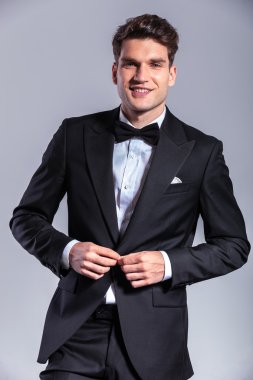 Onun smokin unbuttoning gülümseyen genç iş adamı