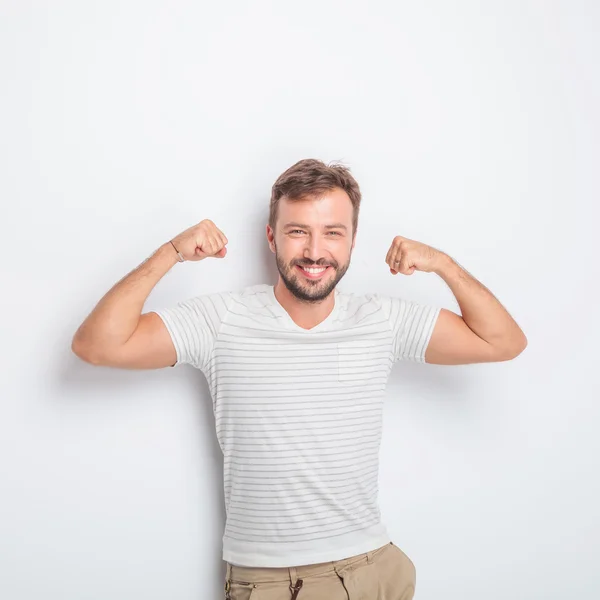 Riendo joven en forma casual hombre flexionando sus músculos — Foto de Stock