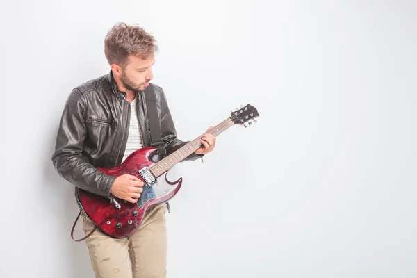 Молодой гитарист в кожаной куртке играет — стоковое фото