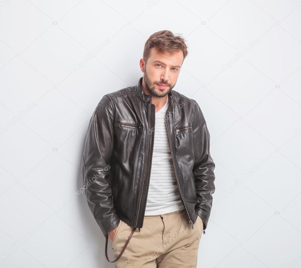 casual young man wearing leather jacket is standing