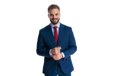 Happy businessman wearing blue suit and red tie, adjusting sleeves and looking forward isolated on white background