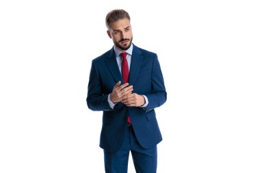 Worried elegant businessman wearing blue suit rubbing hands together and looking to side on white background