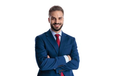 Confident man wearing a blue suit smiling with crossed arms while looking forward isolated on white background