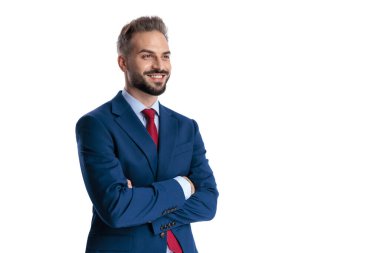 Mavi takım elbiseli kendine güvenen işadamı kollarını kavuşturup beyaz arka planda yer almaya çalışıyor.