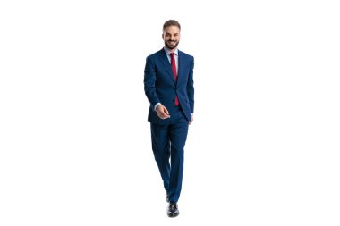 Happy elegant businessman in blue suit smiling while walking and looking forward on white background